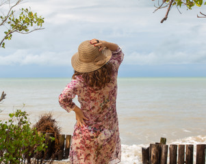 A beautiful woman with a summer hat looking to the sea