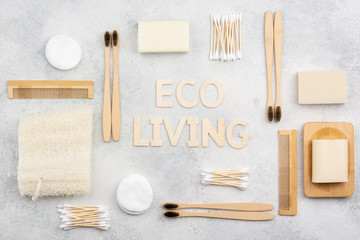 Eco living concept. Bamboo toothbrushes, handmade packaging free soap and shampoo bars, cotton buds pads, luffa on the white concrete marble table top, top view, selective focus