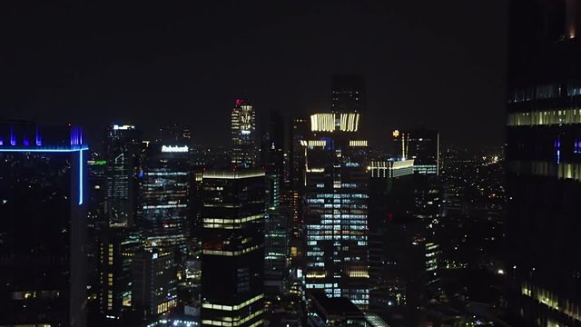 JAKARTA, Indonesia - October 07, 2019: Beautiful aerial scenery of modern skyscrapers exterior in central business district with night lights. Shot in 4k resolution from a drone flying forwards
