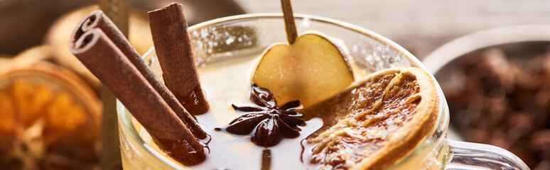 close up view of delicious pear mulled wine with spices and dried citrus i glass, panoramic shot