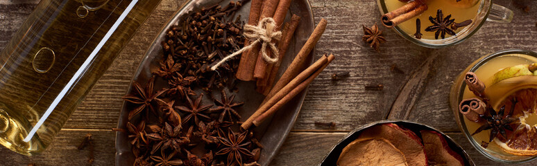 top view of warm pear mulled wine with spices and dried citrus on wooden table, panoramic shot