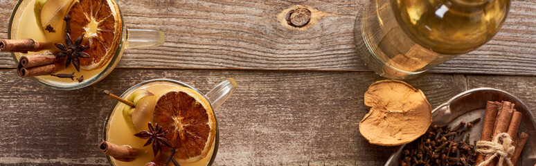 top view of warm pear mulled wine with spices and dried citrus on wooden rustic table, panoramic shot