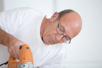 man cutting wood plank using electric jig saw