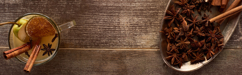top view of traditional warm pear mulled wine with spices and dried citrus on wooden rustic table, panoramic shot