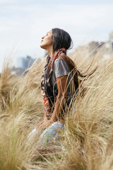 Bolivian girl sitting on high grass looking at the sky