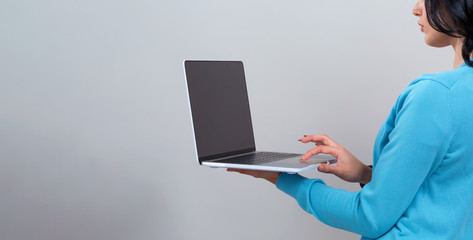 Young woman with a laptop computer on a gray background