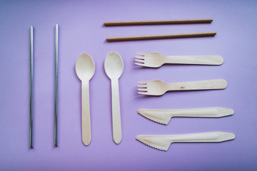 Eco friendly reusable products: Spoon, fork, knife and straws on pink background.