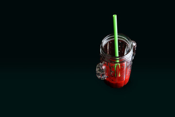 glass of tomate juice in with straw withblack bckground