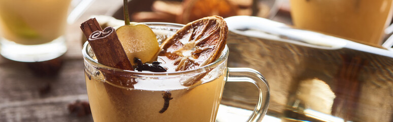 delicious pear mulled wine with spices and dried citrus on wooden table, panoramic shot