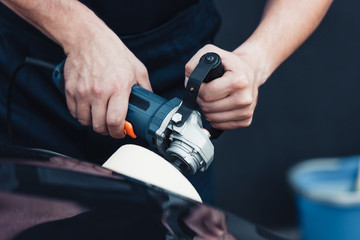 partial view of car cleaner polishing black car with buffer machine