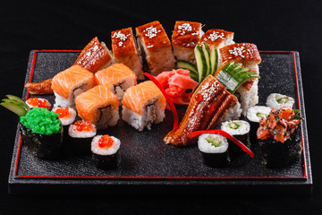 Sushi dragon with eel, cucumber and avocado on a black background. Japanese food, tasty of meal for lunch