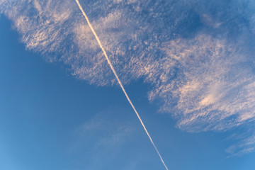 Sky morning evening with central diagonal contrail cirrus clouds