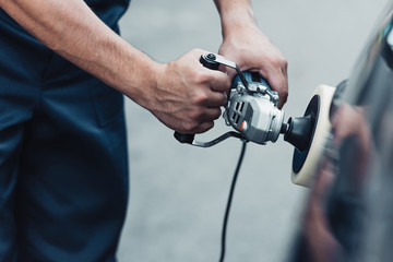 partial view of car cleaner polishing car with buffer machine