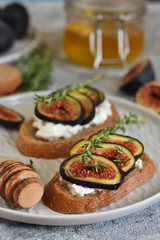 Toasts with ricotta, figs and honey for breakfast on a concrete background. Gourmet breakfast.