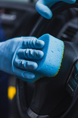 cropped view of car cleaner wiping steering wheel with sponge