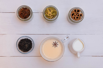 Cup of indian milk tea (chai) with masala tea ingredients