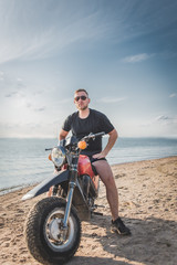 Fototapeta na wymiar Man on motorcycle on beach sea background.