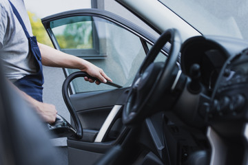 cropped view of car cleaner vacuuming car front door