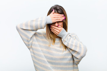 young pretty woman covering face with both hands saying no to the camera! refusing pictures or...
