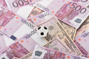 top view of toy soccer ball on euro and dollar banknotes, sports betting concept