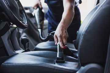 Cropped view of car cleaner vacuuming drivers seat in car - obrazy, fototapety, plakaty