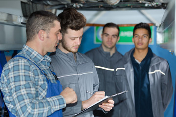 Obraz na płótnie Canvas mechanic and trainees under car