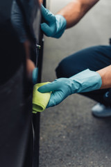 cropped view of car cleaner wiping car wheel with rag