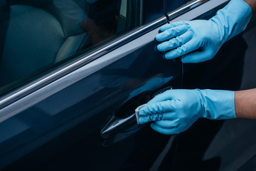 partial view of car cleaner polishing black car door handle