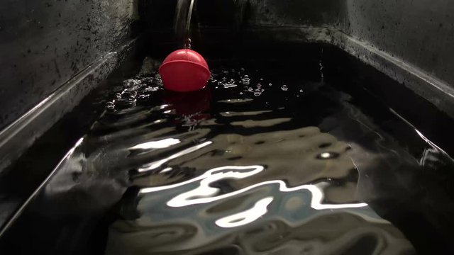 Ripples and bubbles inside a cold water storage tank as it fills up