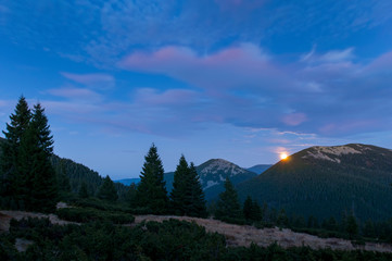 Colorful evening sky over mountains and forest