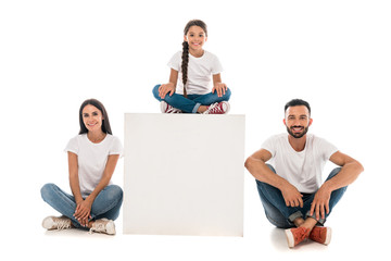 happy kid sitting on cube near cheerful parents isolated on white