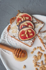 Fig toast with cheese, honey and pine nuts on a white plate. Rustic breakfast or lunch. Pine nuts...