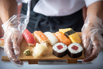 sushi chef serving sushi platter with palastic gloves