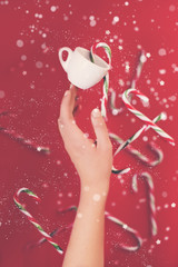 High angle shot of a group of Christmas candy canes falling on a red background.