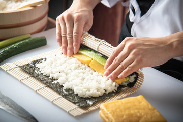 sushi chef making roll sushi with cucumber and egg