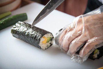 sushi chef making roll sushi with cucumber and egg