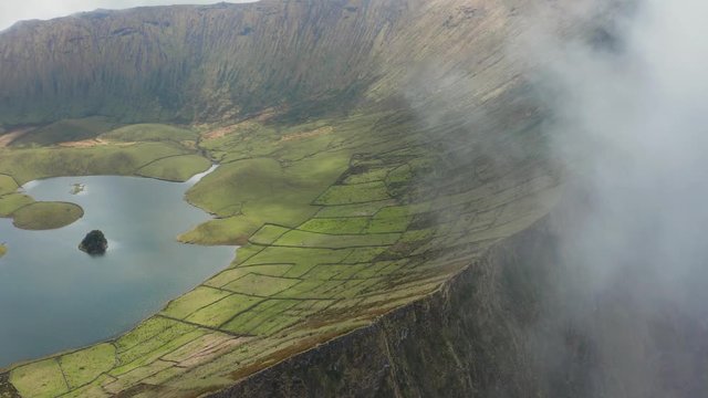 Aerial of caldera from white cloud. Green slopes of Caldeirao volcano, Corvo, Azores