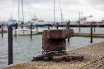 The port of Sassnitz on the German Baltic Sea. A bollard for mooring ships on the quay wall in the foreground. In the background ships blurred with beautiful bokeh.