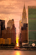 Manhattanhenge in NYC, along the 42nd street as viewed from Queens, across East River. Manhattanhenge is an event during which the setting sun is aligned with the main street grid.