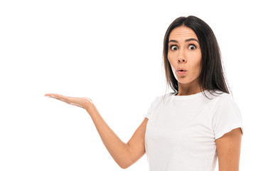 young surprised woman pointing with hand while looking at camera isolated on white