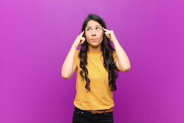 young pretty latin woman looking concentrated and thinking hard on an idea, imagining a solution to...