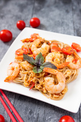 Soba noodles with vegetables and shrimps  on a white plate. Asian food creative concept.