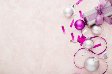 Christmas or New Year composition. Xmas purple and silver decorations: ribbons and balls on pink pastel background. Flat lay, top view, copy space, frame.