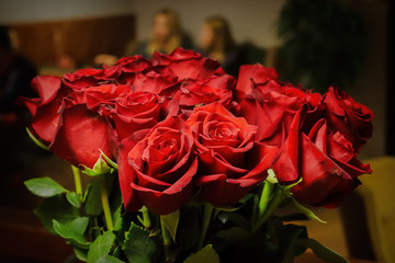 Bouquet of red roses on a wooden table background in a cafe.