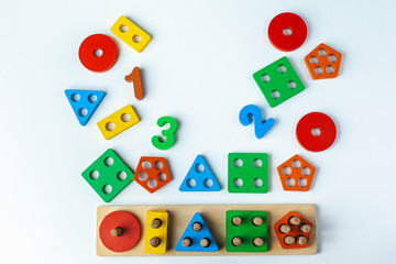 Fototapeta na wymiar Wooden toy for learning numbers and shapes. Numbers from one to five. Multi-colored figures circle, square, rectangle, triangle, five gon. Child plays Montessori game. Kid collects wooden toy sorter. 