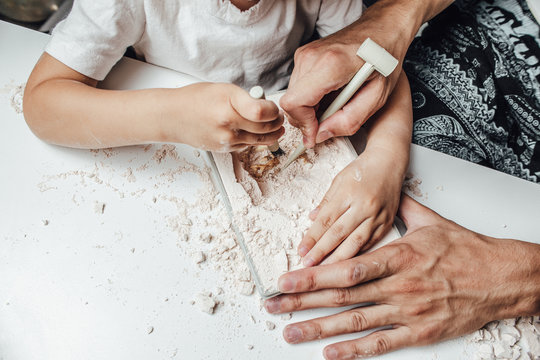 A child plays an archaeologist excavated. Hands close up. Children having fun with archaeology excavation kit in kindergarten and early childhood environment. 