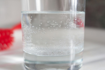 A glass of city tap water with air bubbles stuck to the side of the container