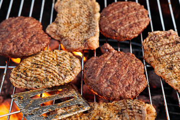 Barbecue grill. A man fries meat steaks and meatballs for hamburgers, turns the meat over with tongs.