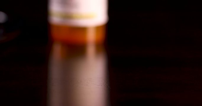 Slow Panning of Non-proprietary Medicine Bottles, Pills and Stethoscope on Dark Wood Surface.