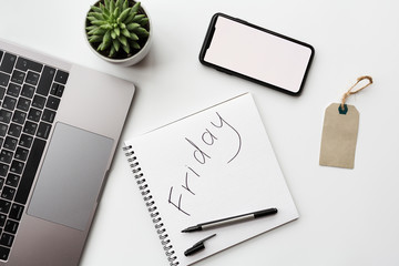 Creative promotion composition for Black friday sale on white background, next laptop, mobile phone, pen, succulent plant, label. Flat lay, top view, overhead, mockup, template